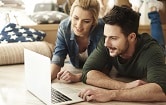 couple on the grass looking at computer