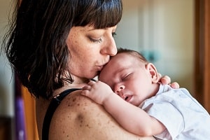 Loving Mother Kissing Baby's Forehead