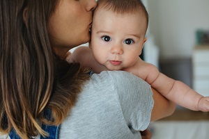 Portrait Of A Young Mother Taking Care Of Her Cute Baby At Home.